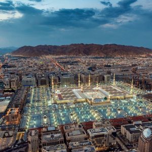 A stunning aerial view of Al-Masjid an-Nabawi in Medina at dusk, showcasing its illuminated grandeur.